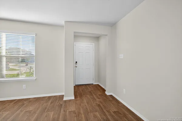 a view of an empty room with wooden floor and a window