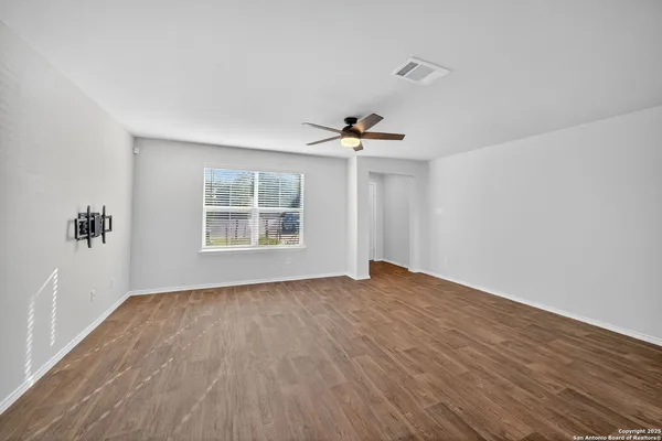 a view of an empty room with a window and wooden floor
