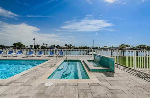 a view of a swimming pool with a yard and palm trees