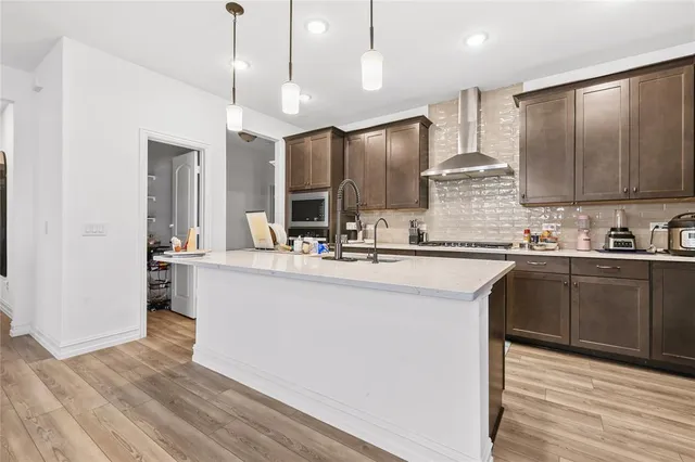a kitchen with stainless steel appliances kitchen island granite countertop a refrigerator a sink dishwasher a stove and white cabinets with wooden floor