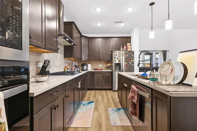 a kitchen with stainless steel appliances granite countertop a sink a stove and a refrigerator