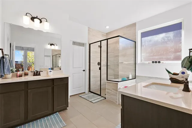 a spacious bathroom with a double vanity sink a large mirror and shower