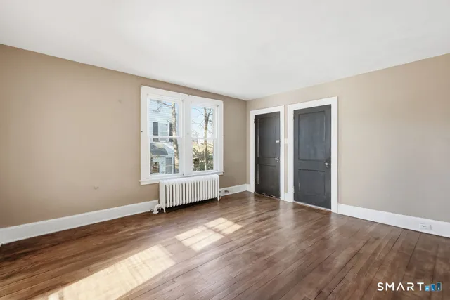 an empty room with wooden floor and window