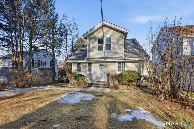 a front view of a house with large trees