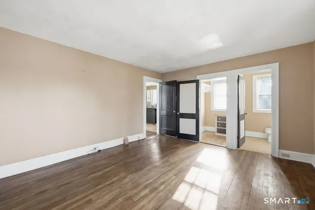 a view of an empty room with window and wooden floor
