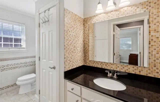 a bathroom with a granite countertop sink toilet a mirror a shower and a sink