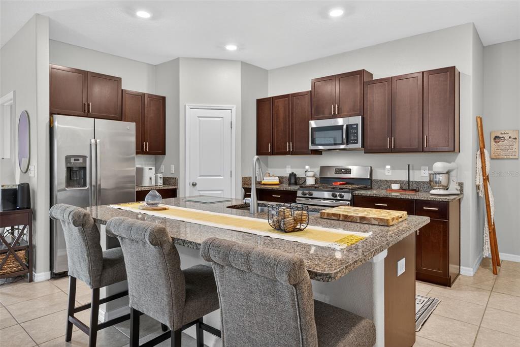 9645 Lemon Drop Loop Ruskin, FL 33573 - Photo 11 of 49 a kitchen with stainless steel appliances granite countertop a stove top oven a refrigerator a sink and a microwave