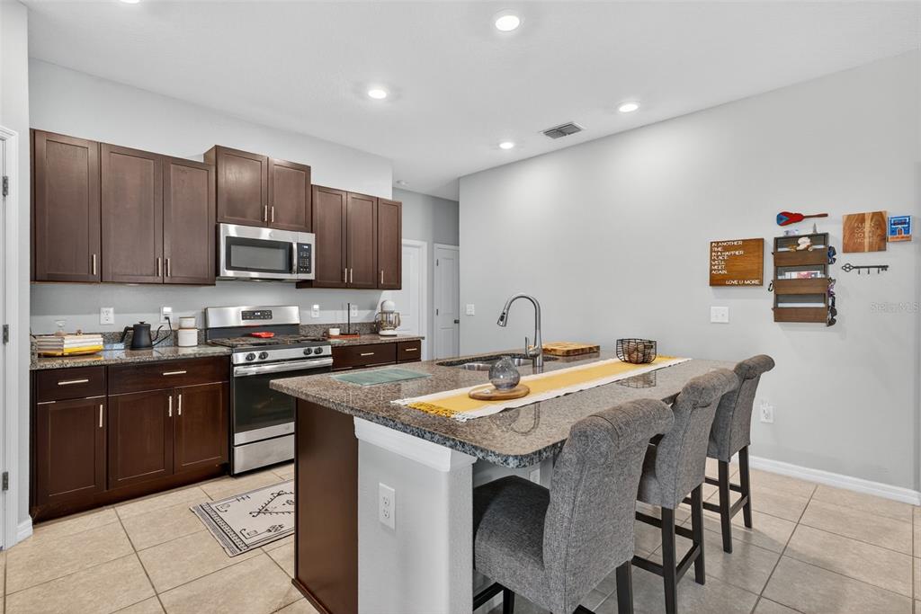 9645 Lemon Drop Loop Ruskin, FL 33573 - Photo 10 of 49 a kitchen with stainless steel appliances granite countertop a stove top oven a sink a refrigerator and a microwave