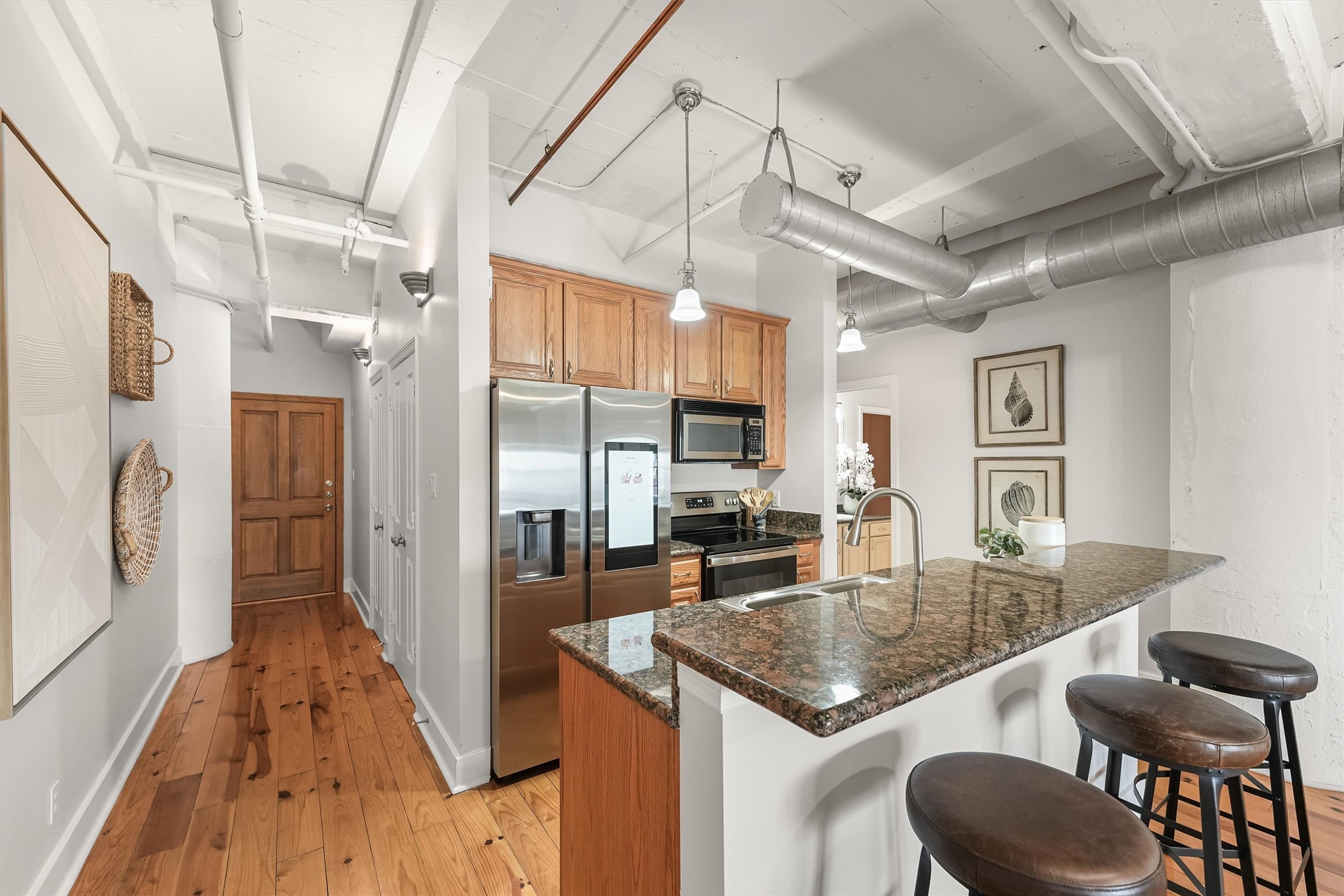 104 21st Street, Unit 203 Galveston, TX 77550 - Photo 4 of 27 a kitchen with stainless steel appliances granite countertop a table chairs in it and wooden floors