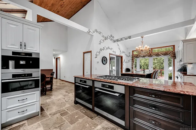 a kitchen that has a lot of cabinets a island a stove and a window