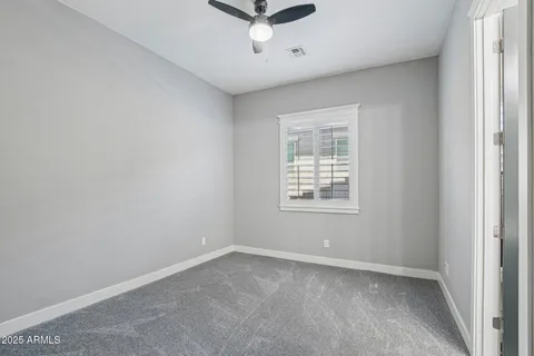 an empty room with a window and a ceiling fan