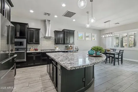 a kitchen with stainless steel appliances granite countertop wooden cabinets a refrigerator a stove a sink and a oven