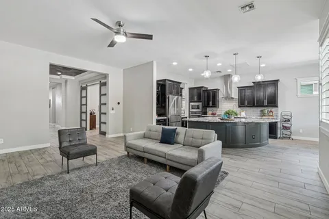 a living room with furniture kitchen area and a wooden floor