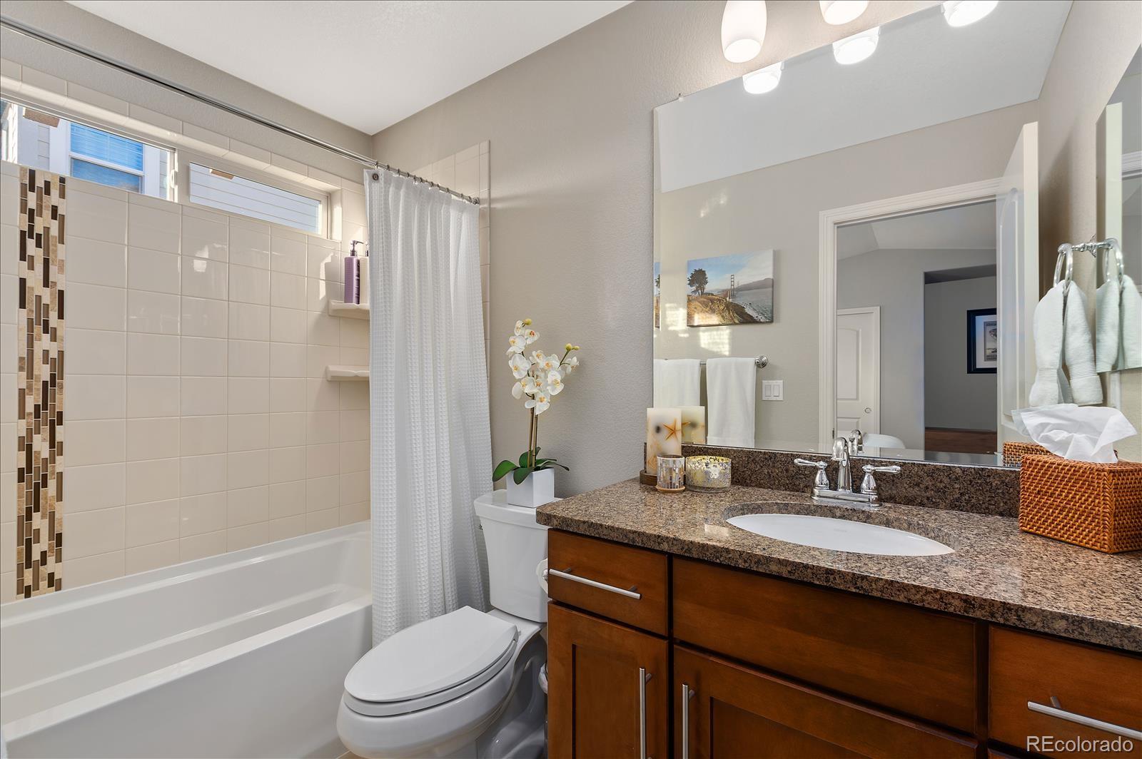 10654 Sundial Rim Road Highlands Ranch, CO 80126 - Photo 13 of 40 a bathroom with a granite countertop sink toilet a large mirror a shower and a bathtub