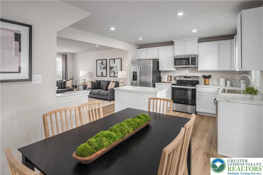 a view of a kitchen with kitchen island stainless steel appliances refrigerator stove dining table and chairs