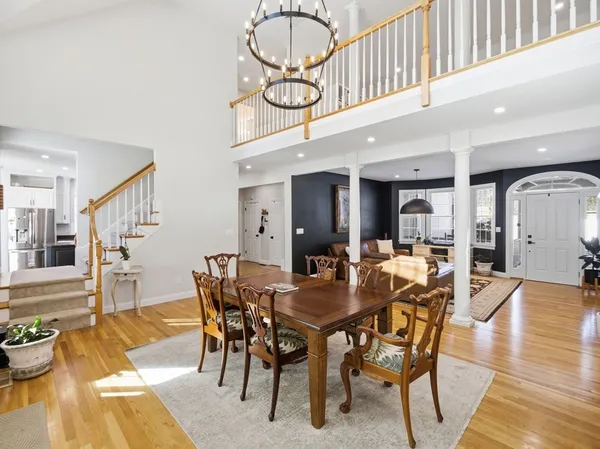 a view of a dining room and livingroom with furniture wooden floor a rug a fireplace and a chandelier