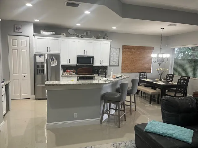 a dining hall with stainless steel appliances kitchen island granite countertop a table and chairs