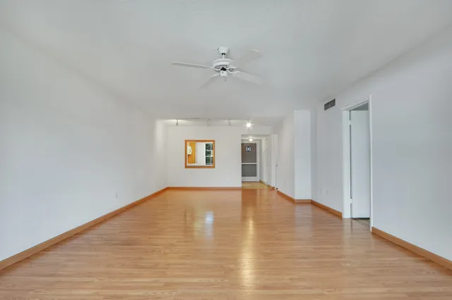 a view of an empty room with a window and wooden floor
