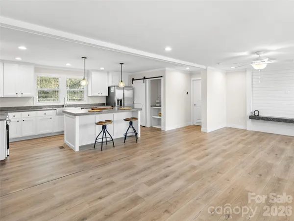 a kitchen with stainless steel appliances granite countertop a stove top oven a chimney cabinets and wooden floor