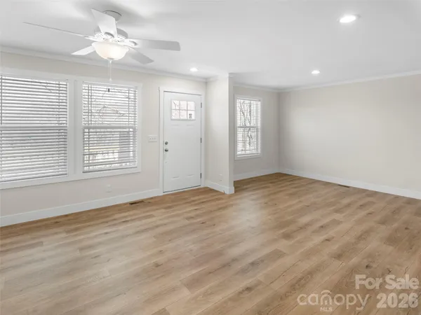 an empty room with wooden floor and windows