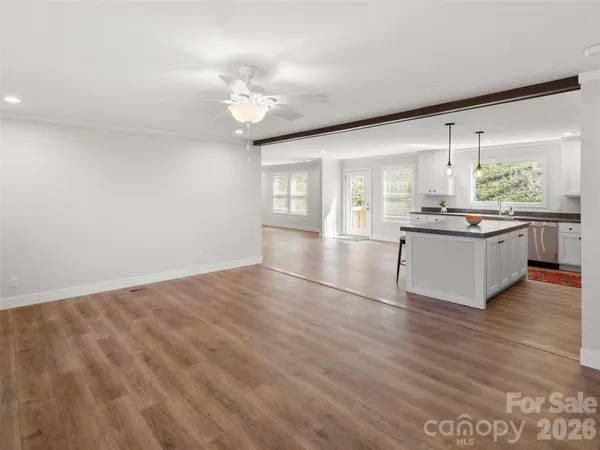 a living room with stainless steel appliances kitchen island granite countertop a sink cabinets and wooden floor
