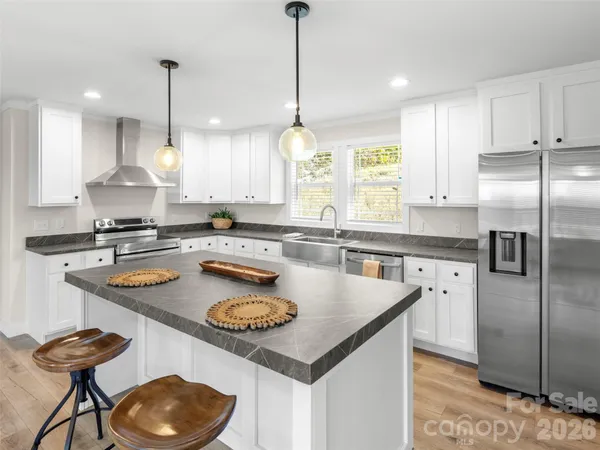 a kitchen with stainless steel appliances granite countertop a sink a oven and a wooden floor