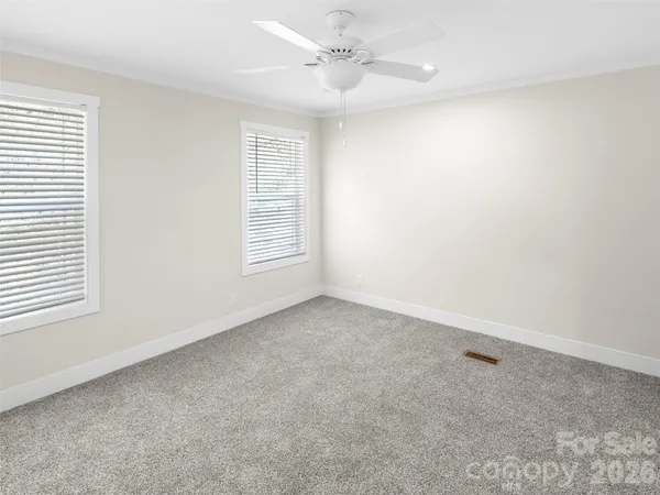 an empty room with a ceiling fan and natural light