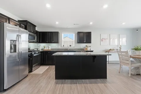 a kitchen with stainless steel appliances granite countertop a refrigerator a sink a stove a microwave and a refrigerator