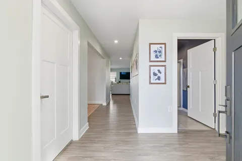a view of a hallway with wooden floor and a living room