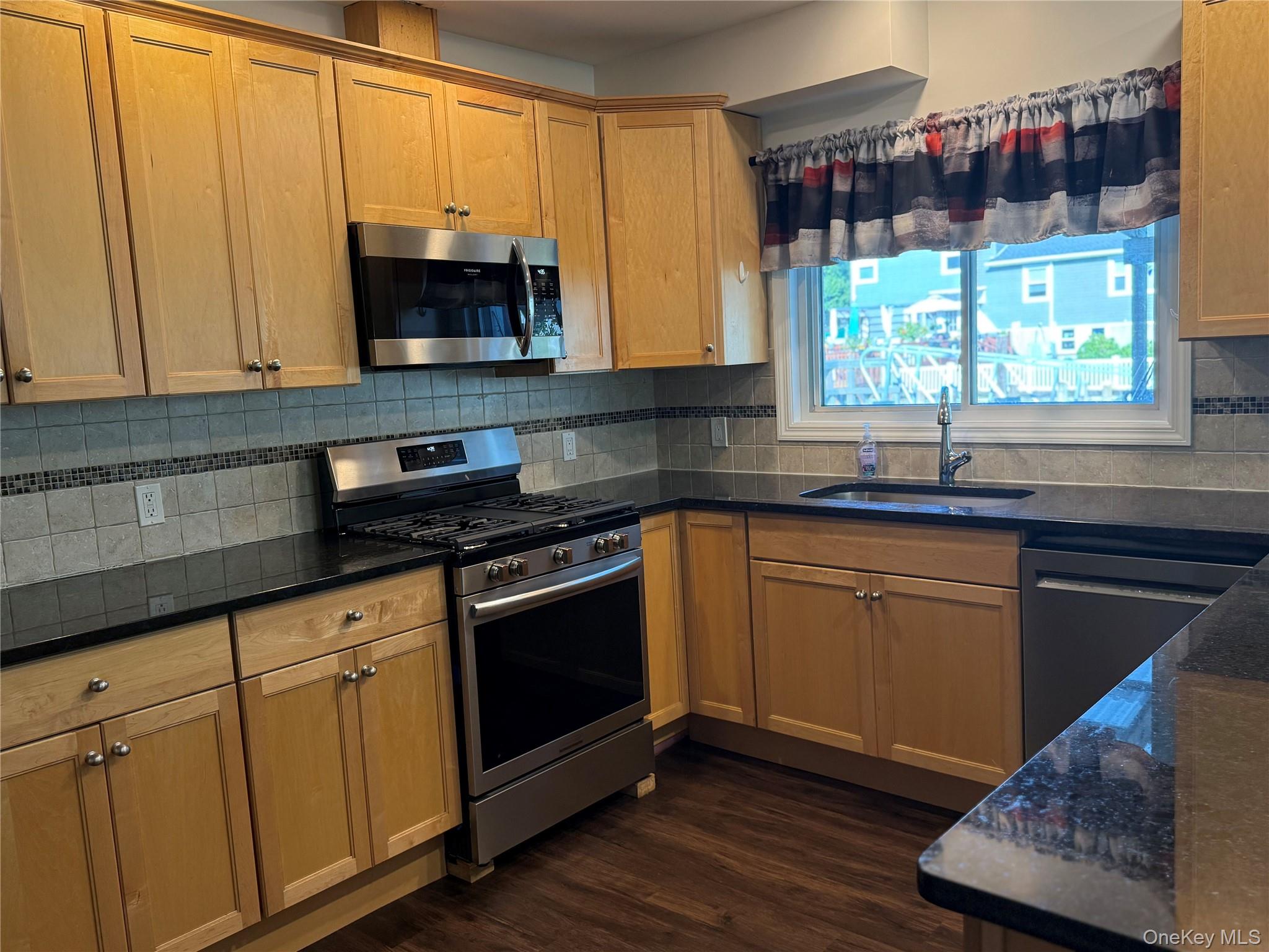 55 Lester Avenue Freeport, NY 11520 - Photo 9 of 38 a kitchen with stainless steel appliances granite countertop a sink a stove and a microwave