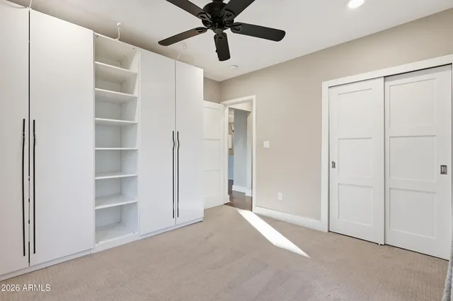 an empty room with ceiling fan and windows