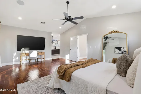 a spacious bedroom with a bed and wooden floor