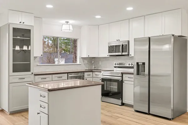 a kitchen with stainless steel appliances granite countertop a refrigerator a stove a sink and a microwave