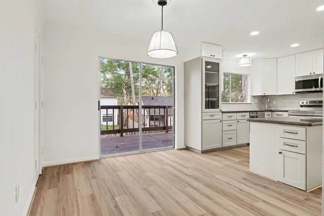 a kitchen with stainless steel appliances granite countertop a stove a refrigerator a sink and white cabinets with wooden floor