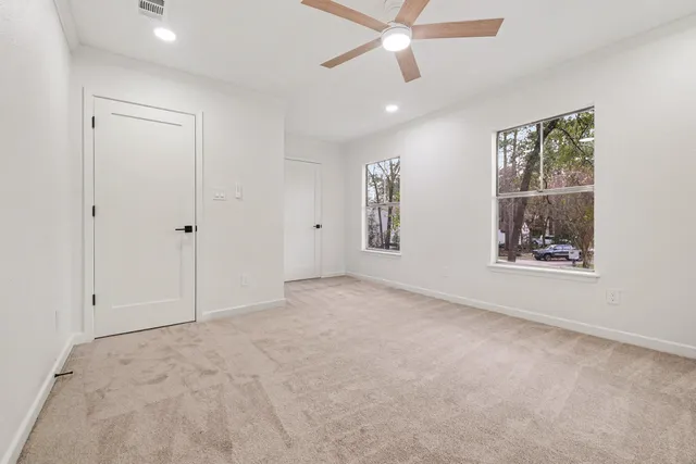 an empty room with windows and fan