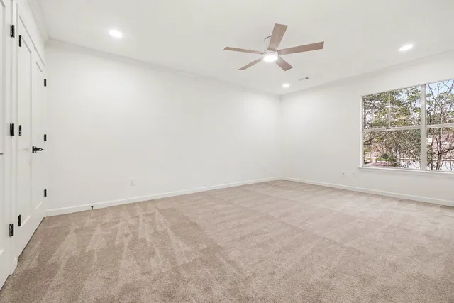 an empty room with window and ceiling fan