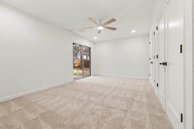 an empty room with ceiling fan and window