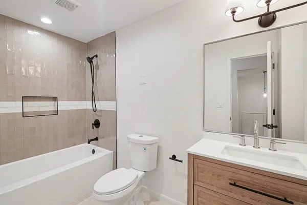 a bathroom with a toilet a sink a mirror a bathtub and vanity