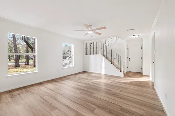a view of an empty room with wooden floor and a window