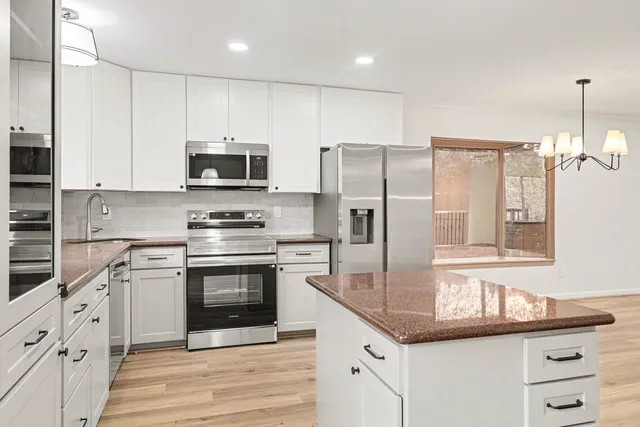 a kitchen with granite countertop a stove a sink and a refrigerator