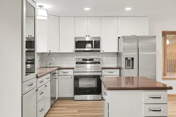 a kitchen with stainless steel appliances granite countertop a stove a refrigerator and a microwave