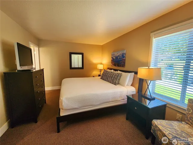 a bedroom with a bed and a lamp on dresser