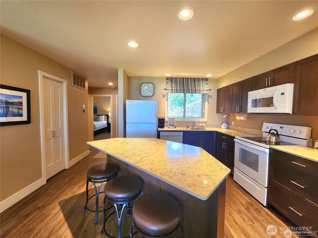 a kitchen with stainless steel appliances granite countertop a sink a stove a refrigerator cabinets and dining table