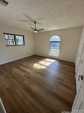 a view of an empty room with a window and wooden floor