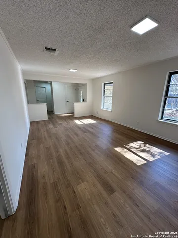 a view of empty room with wooden floor and window