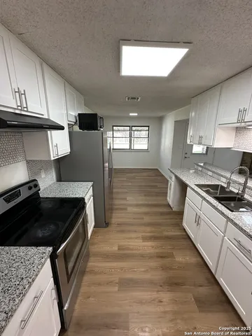 a kitchen with granite countertop a stove and cabinets