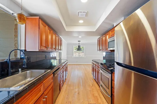a kitchen with granite countertop a sink a counter top space stainless steel appliances and cabinets