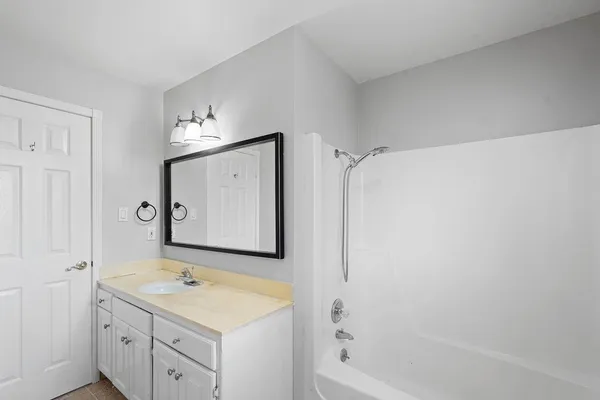 a bathroom with a granite countertop sink mirror vanity and bathtub