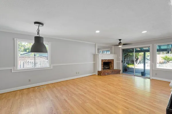 an empty room with windows fireplace and wooden floor