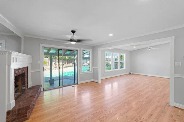 a view of an empty room with wooden floor and a fireplace